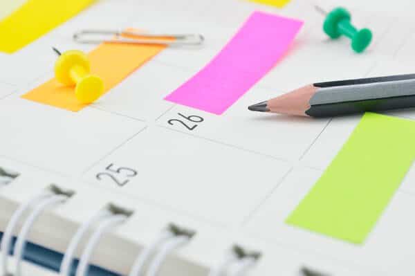 Pencil with post It notes and pin on business diary page Planner and pencil with post it notes.